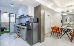 Una cocina moderna con electrodomésticos de acero inoxidable, un comedor con sillas naranjas y un ventanal grande.