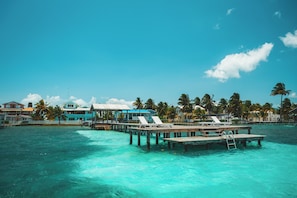 A tropical resort with a pier extending into turquoise waters, featuring overwater bungalows and palm trees. - Casa Al Mar, Belize (St. George's Caye)