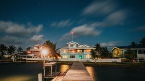 A waterfront property with a dock leading to a house with multiple levels and a flagpole. - Casa Al Mar Belize (St. George's Caye)