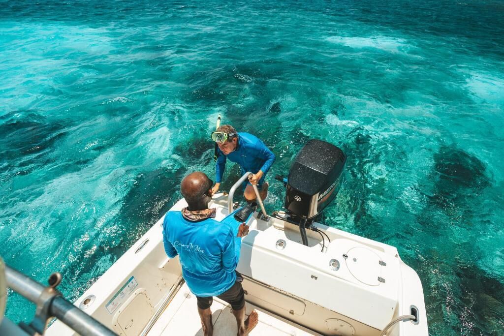 Un barco con dos personas a bordo, una manejando y la otra de pie.