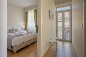 Une chambre à coucher comprenant un lit, des tables de chevet, une fenêtre avec des rideaux et un balcon avec une balustrade.