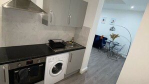 A modern kitchen with stainless steel appliances, grey cabinets, and a built-in washing machine. - Stylish 2bedroom Flat in London|free parking|Contractors (Wallington)