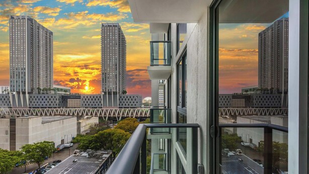 Ein Hochhaus mit Sonnenuntergangsblick, moderne Architektur und eine Brücke im Vordergrund.