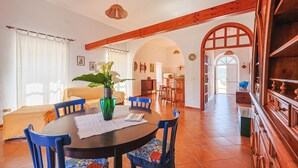 A dining area with a round table, blue chairs, a green vase, and a wooden ceiling beam. - Casa Santo Stefano – Panoramic Villa with Sea Views, Pet-Friendly, 6 km from the Beach (Santo Stefano)