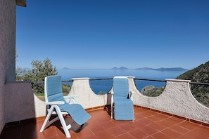 Un balcón con dos sillones de relax y vista al mar.