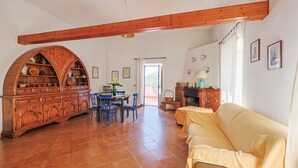 A spacious living area with a wooden cabinet, a sofa, a dining table with chairs, and a fireplace. - Casa Santo Stefano – Panoramic Villa with Sea Views, Pet-Friendly, 6 km from the Beach (Santo Stefano)