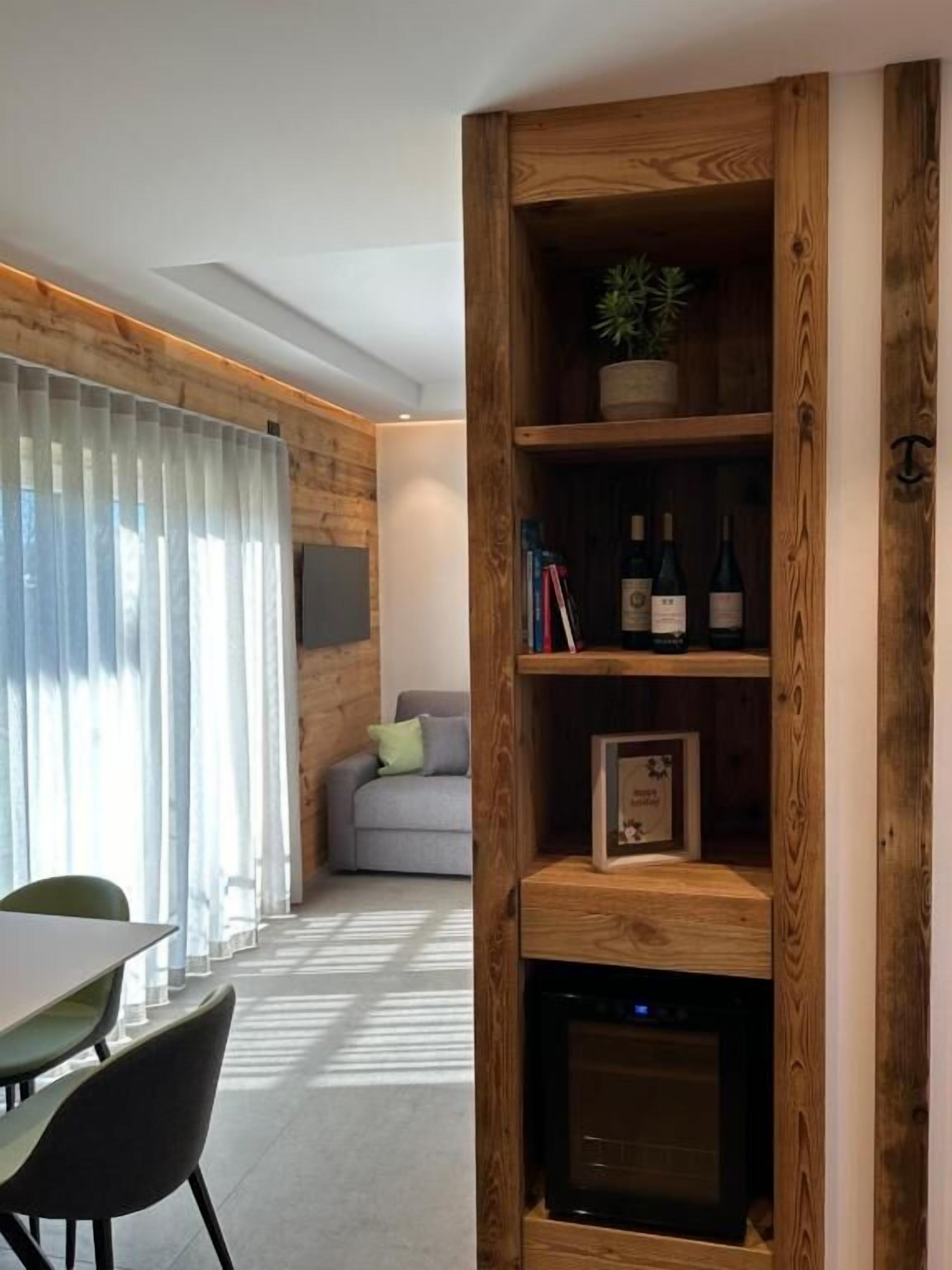 Un salon moderne avec une bibliothèque en bois, un canapé gris et un coin repas comprenant des chaises et une table.
