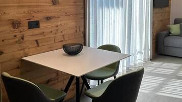 A modern dining area with a wooden wall, a white table, and green chairs.