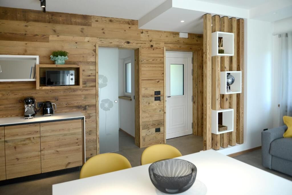 Een moderne keuken met houten details, een eethoek met gele stoelen en een grijze bank.