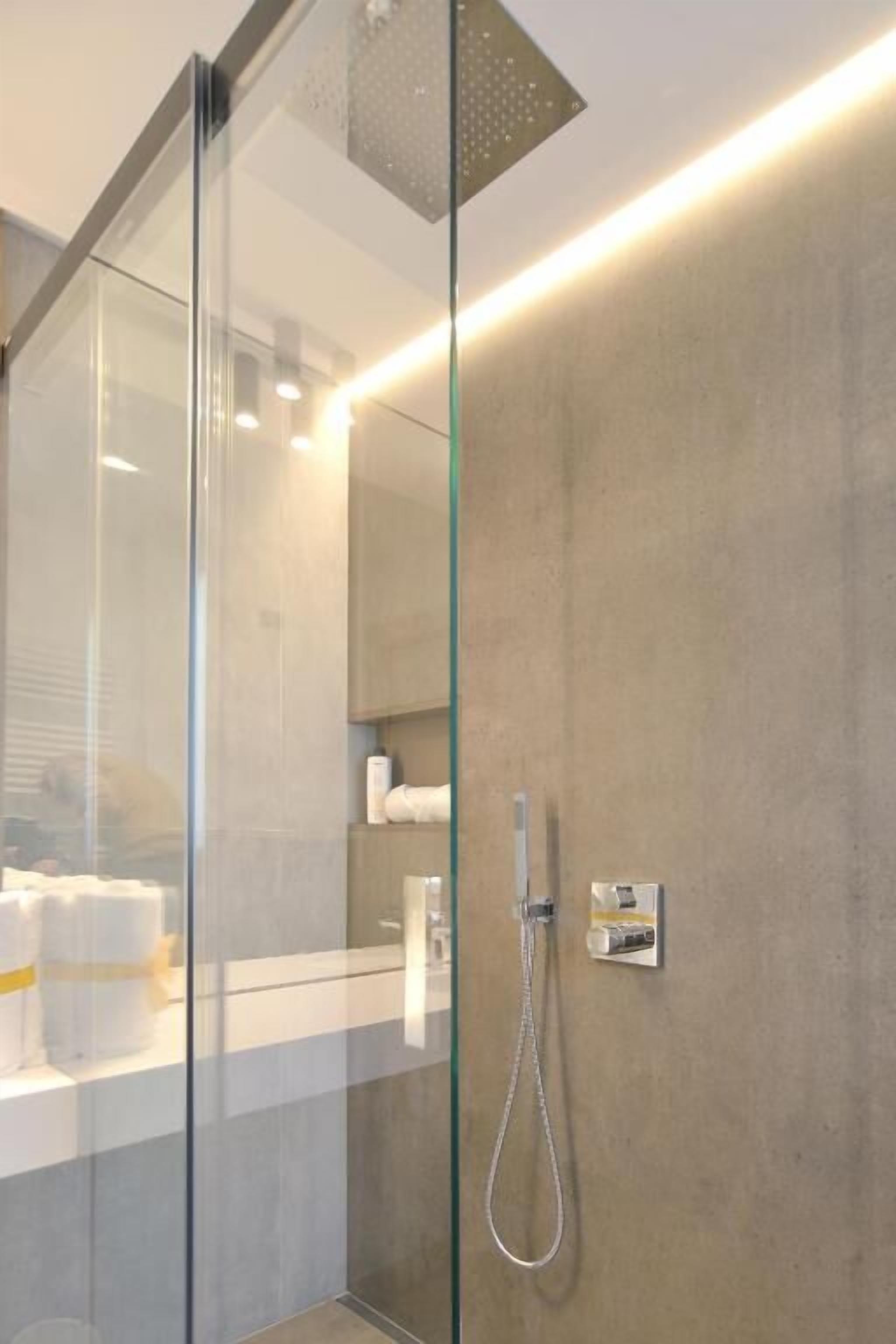 Een moderne badkamer met een glazen douchecabine, een douche en een handdoekhouder.