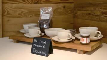 Une collection de tasses et de soucoupes blanches est exposée sur un présentoir en bois, accompagnée d’une pancarte sur laquelle on peut lire : « Un petit geste de bienvenue ! » et d’un pot de miel.