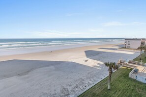A beach view with a building adjacent to the shore. - 🌊Direct Oceanfront with Fabulous Views | Great Amenities | Ebb Tide 407🌊 (New Smyrna Beach)