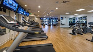 Une salle de sport équipée de plusieurs tapis de course, de vélos d’exercice et d’appareils de musculation.