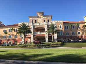 Ein Hotel mit einer symmetrischen Fassade, mehreren Balkonen und Palmen im Vorgarten.