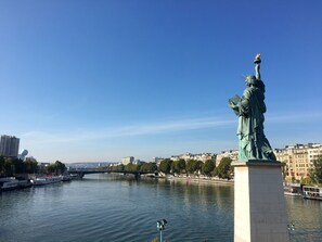A statue of a historical figure on a pedestal by a river with buildings in the background. - 1 bedroom with A/C in a new building close to the Eiffel Tower (Paris)