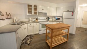 Een moderne keuken met witte kastjes, een houten tafel en een inbouwoven.