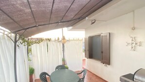 A patio with a table and chairs, a grill, and a TV mounted on the wall. - Central and very relaxing facility (Alezio)