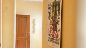 A hallway with a wooden door, a bench, and a wall with a colorful artwork. - Central and very relaxing facility (Alezio)