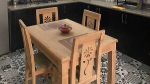 A modern kitchen with white cabinets, a black countertop, and a wooden dining table with chairs. - Apartment Youssef 5 min walk from the beach (Essaouira)