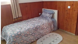 A small, neatly arranged bedroom with a wooden headboard, a patterned bedspread, and a small rug on the floor. - Apartment Youssef 5 min walk from the beach (Essaouira)