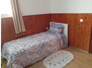 A small, neatly arranged bedroom with a wooden headboard, a patterned bedspread, and a small rug on the floor. - Apartment Youssef 5 min walk from the beach (Essaouira)