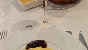 A plate with a slice of meat terrine, a glass of white wine, and a small dish of butter on a table. - Ground floor room with unlimited access to outdoor spa (Porcaro)