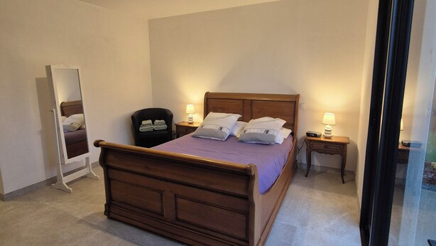 A bedroom with a wooden bed, two bedside tables with lamps, a mirror, and a door. - Ground floor room with unlimited access to outdoor spa (Porcaro)