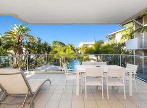 Ein Balkon mit Pool, weißer Möbel und tropischer Bepflanzung.