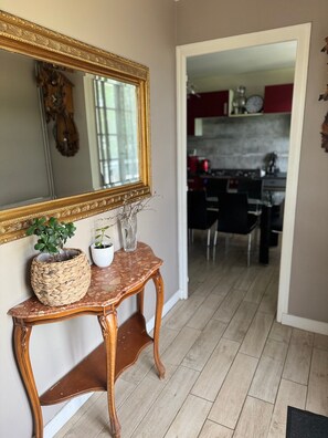 A hallway with a mirror, a woven basket, a vase, and a console table. - Beautiful House with View of the Vienne (Le Palais-sur-Vienne)