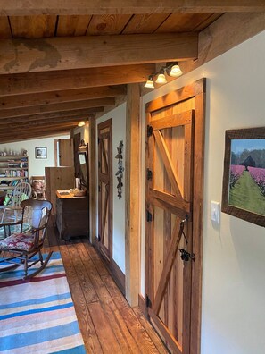 A rustic hallway with wooden doors and a striped rug. - The Henhouse at Peace Hill Farm (Charles City)
