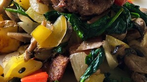 Un plato con un huevo escalfado encima, rodeado de verduras salteadas y carne.