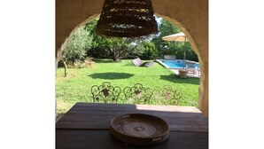 A wooden table with a decorative plate in a courtyard with a pool and lounge chairs. - 18th CENTURY STONE BASTIDE in UZES (La Bastide-d'Engras)
