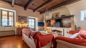 A cozy room with wooden floors, a fireplace, and a bed with red bedding. - 18th CENTURY STONE BASTIDE in UZES (La Bastide-d'Engras)