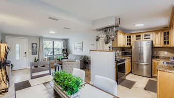 Una cocina moderna con electrodomésticos de acero inoxidable, armarios de madera y un comedor con un centro de plantas.