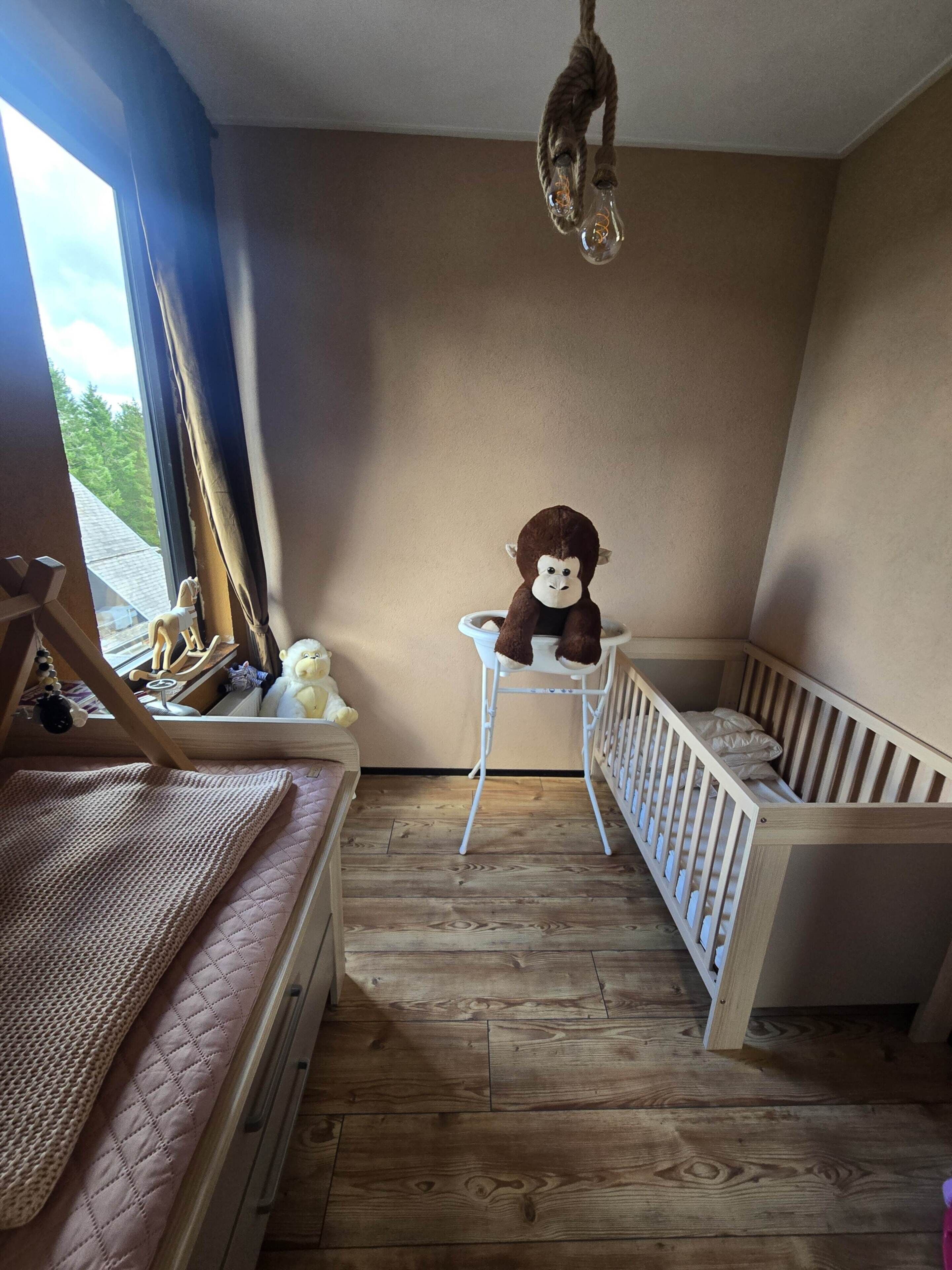 A child's room with a crib, a small table, and a hanging light fixture.