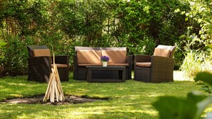 An outdoor seating area with wicker furniture, a central table, and a potted plant. - Idyllically situated apartment Logafeld in the Leeraner Meeden, pet friendly! (Leer (Ostfriesland))
