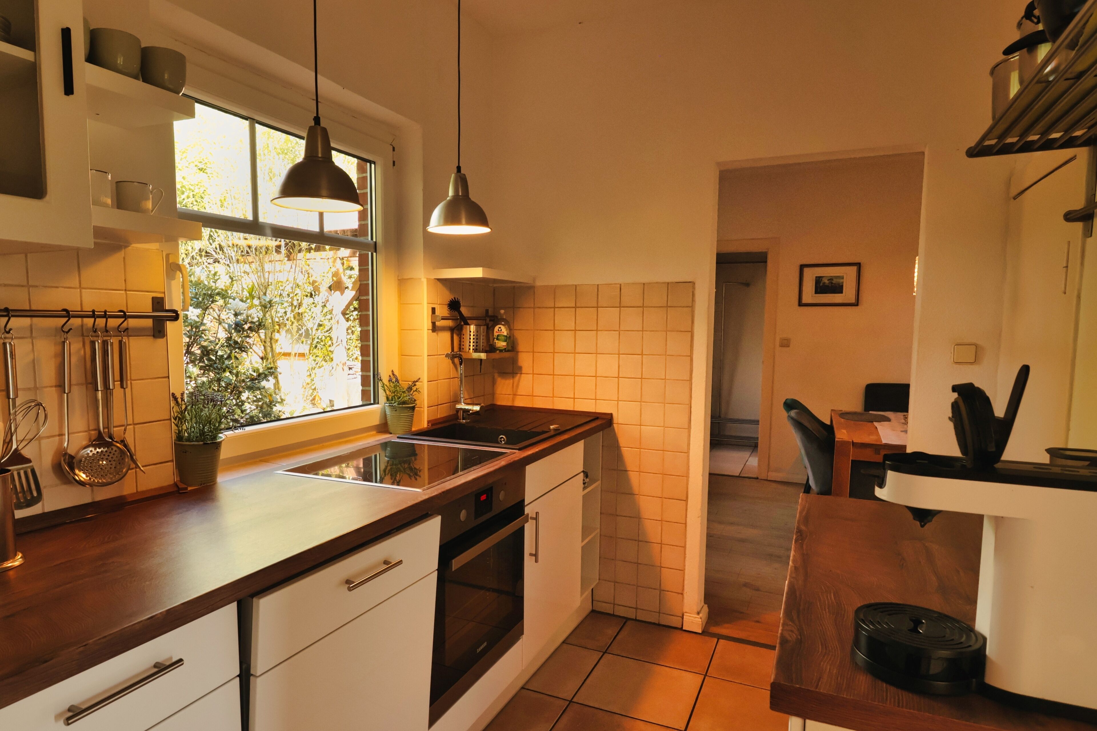 Eine moderne Küche mit einer Holz Arbeitsplatte, Edelstahlgeräten und einer hängenden Pendelleuchte.