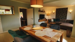 A dining area with a wooden table, chairs, and a hanging light fixture. - Idyllically situated apartment Logafeld in the Leeraner Meeden, pet friendly! (Leer (Ostfriesland))