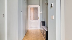 A hallway with a wooden floor, a white door with a textured glass panel, and a small black cabinet with drawers. - Ferrucci 14 by Wynwood House (Milan)