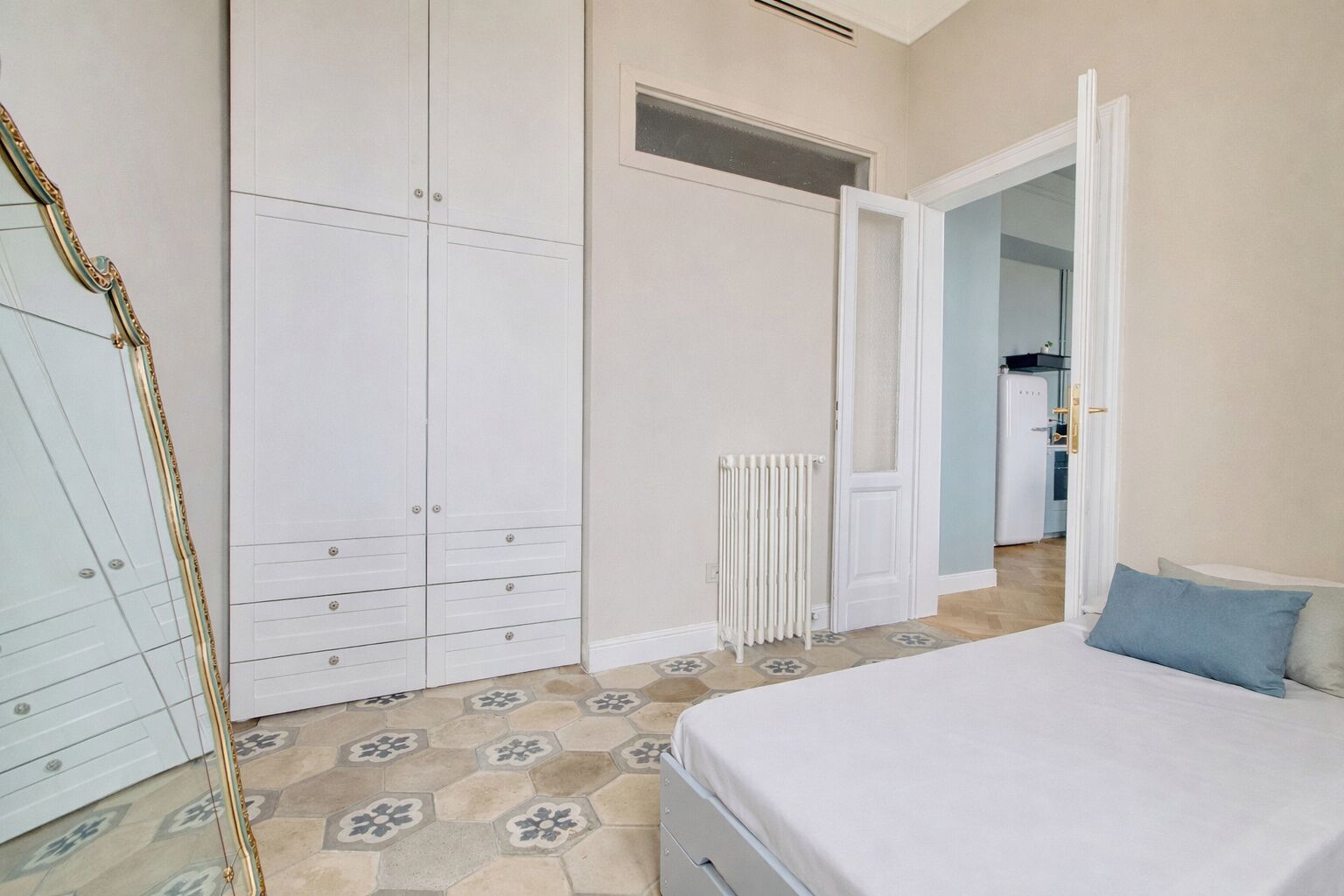 A bedroom with a bed, a wardrobe, and a radiator.