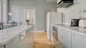 Una cocina moderna con encimera de mármol, horno empotrado y campana extractora negra.