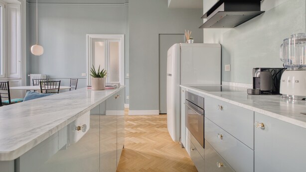 A modern kitchen with a marble countertop, built-in oven, and a black range hood. - Ferrucci 14 by Wynwood House (Milan)