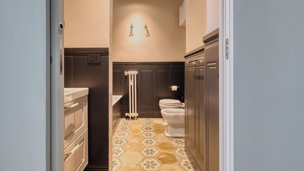 Un pasillo estrecho que conduce a un baño con inodoro, lavabo y radiador.