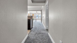 Ein Flur mit Teppichboden, weißen Wänden und einem Deckenventilator.