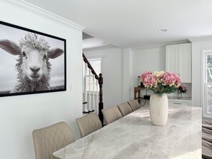 A modern kitchen with white cabinets, a marble countertop, and a vase of flowers. - Spacious Retreat with Game Room  (Norwalk)
