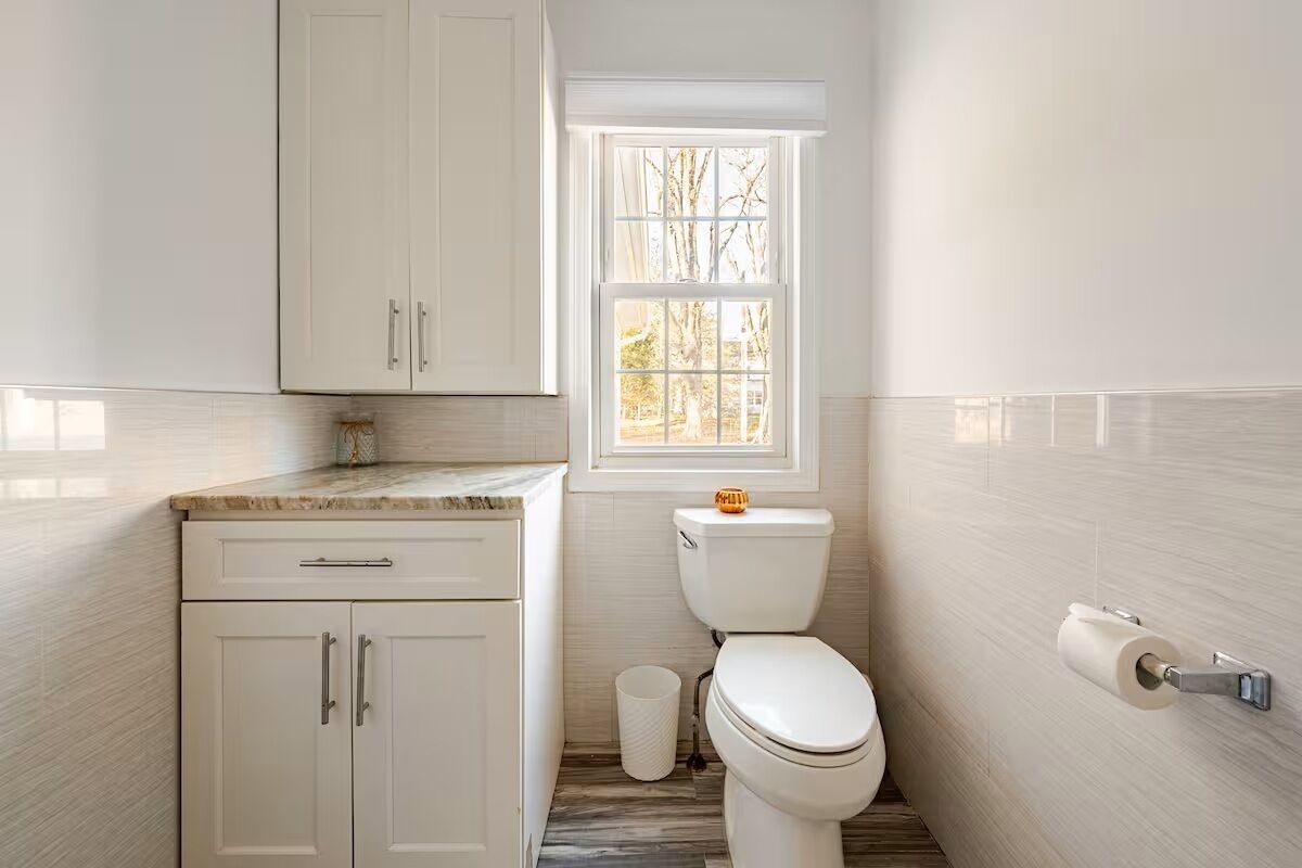 Un baño pequeño y moderno con inodoro, lavabo y armarios.