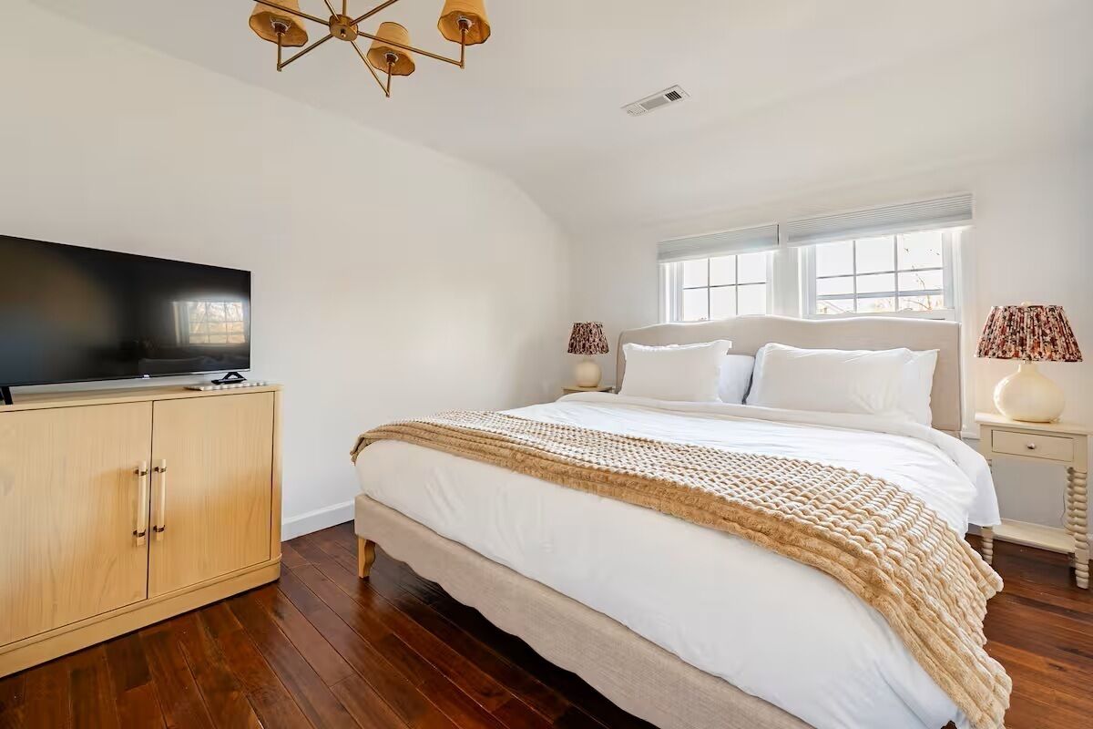 Un dormitorio con una cama grande, un armario de madera y un televisor sobre un mueble.