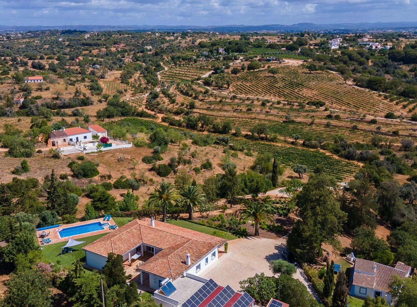 Una extensa propiedad con varias edificaciones, piscina y amplios jardines.