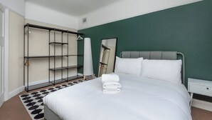 Hotellihuone, jossa on sänky, vaatekaappi ja peili.