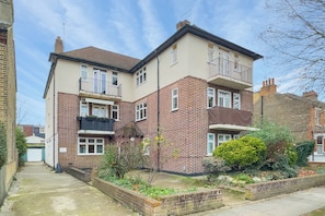A two-story residential building with a brick facade, multiple windows, and a small balcony on the upper floor. - Spacious 2BDR with Dedicated Work Area (Greater London)